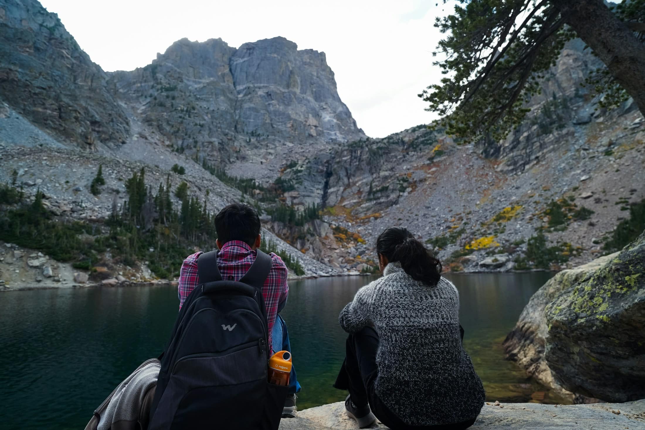 A couple seated on granite above an alpine lake